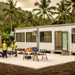 Base vie modulaire installée en Martinique avec bureaux climatisés, outils et équipe de chantier en action sur le site.