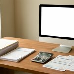 Bureau professionnel organisé avec dossiers vierges, feuilles de documents financiers, calculatrice et ordinateur à écran neutre, dans une ambiance sobre et rassurante.